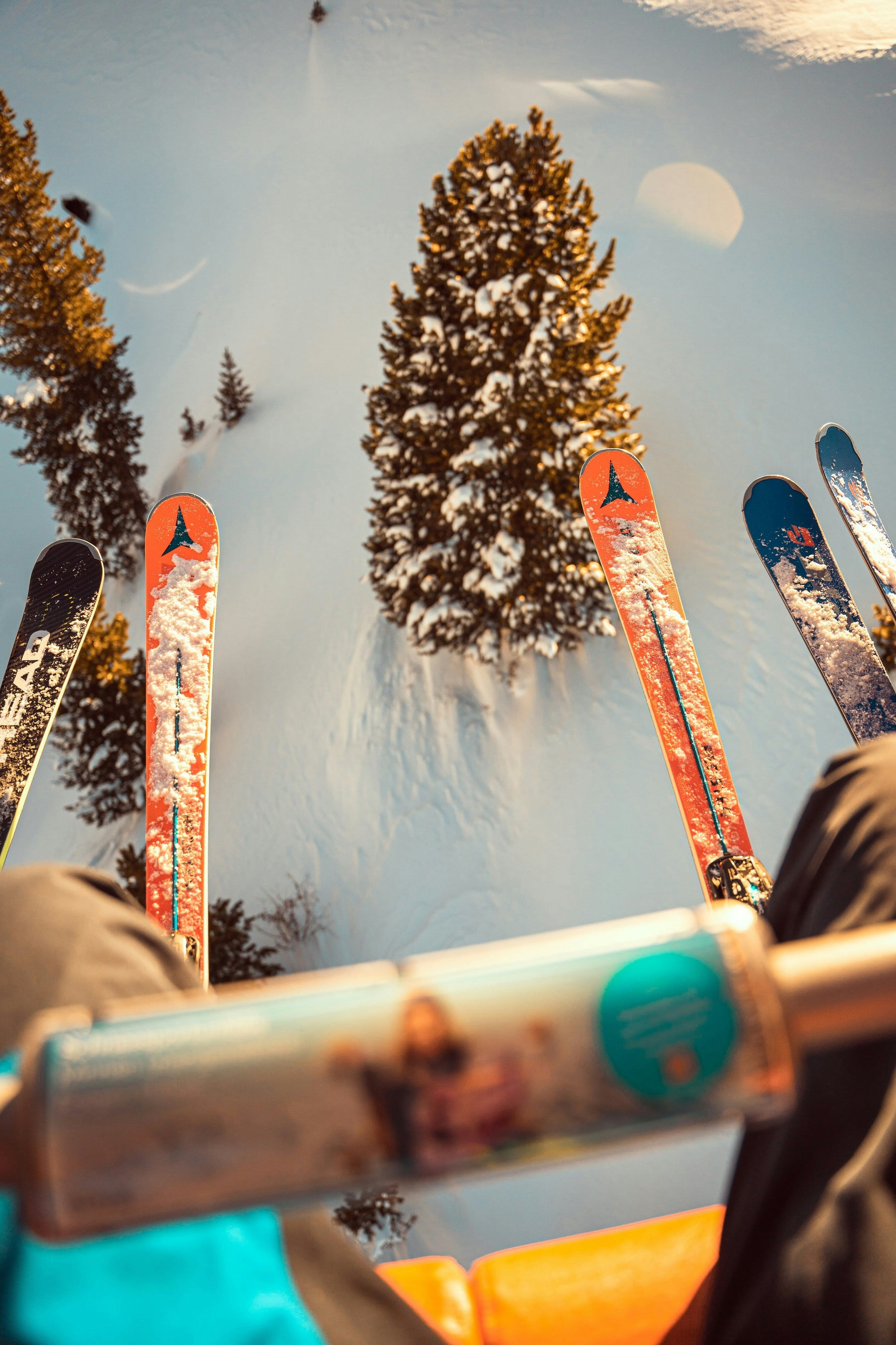 Skis on a chairlift overlooking a snowy mountain slope.