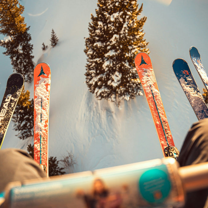 Skis on a chairlift overlooking a snowy mountain slope.