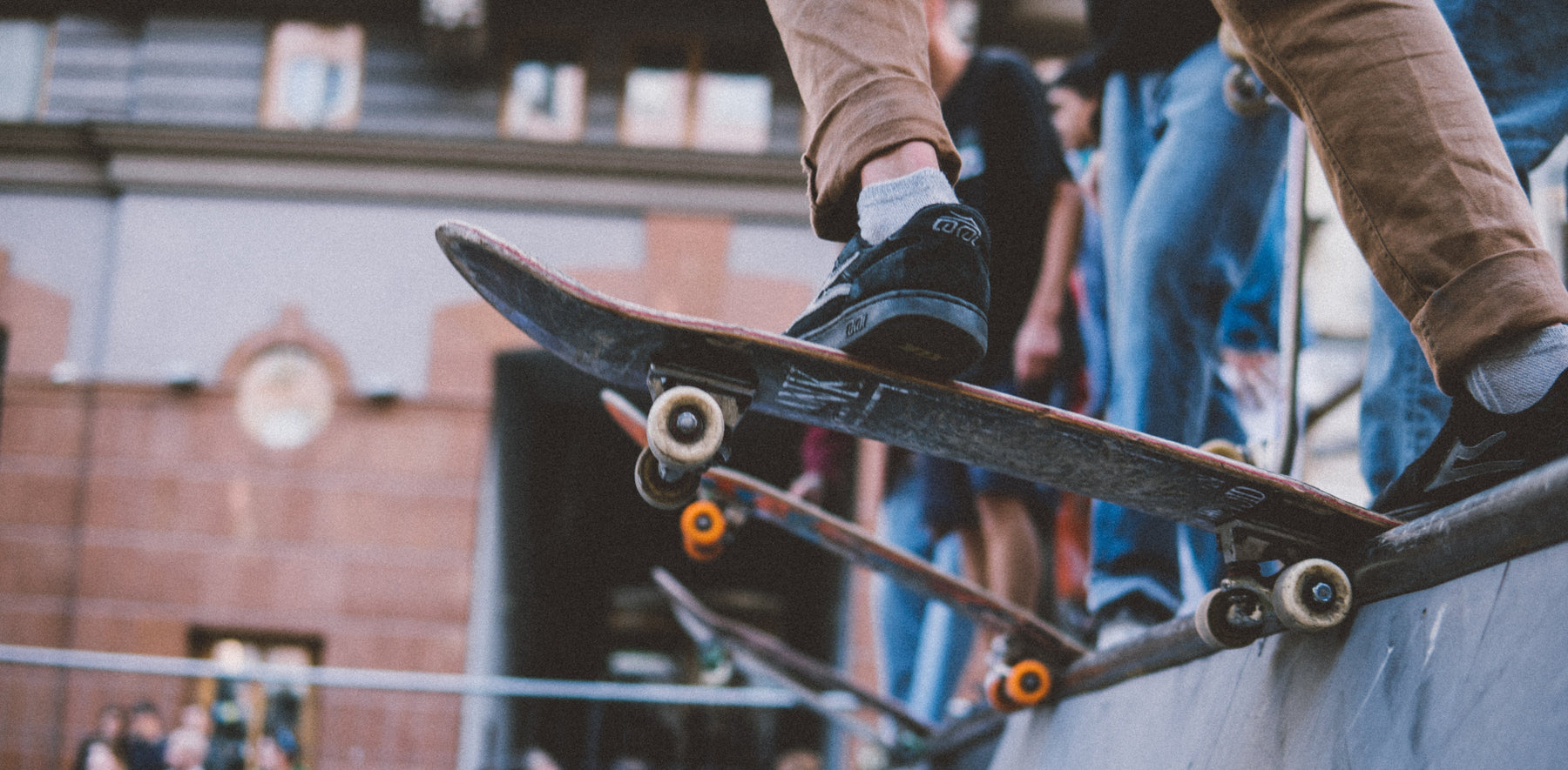 Close-up of skateboarders performing tricks on a skate park ramp.